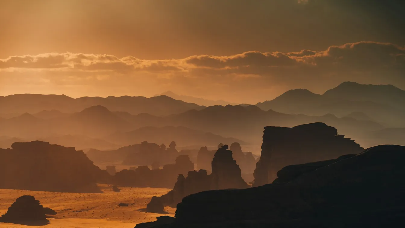the sun is shining over a desert with mountains in the background