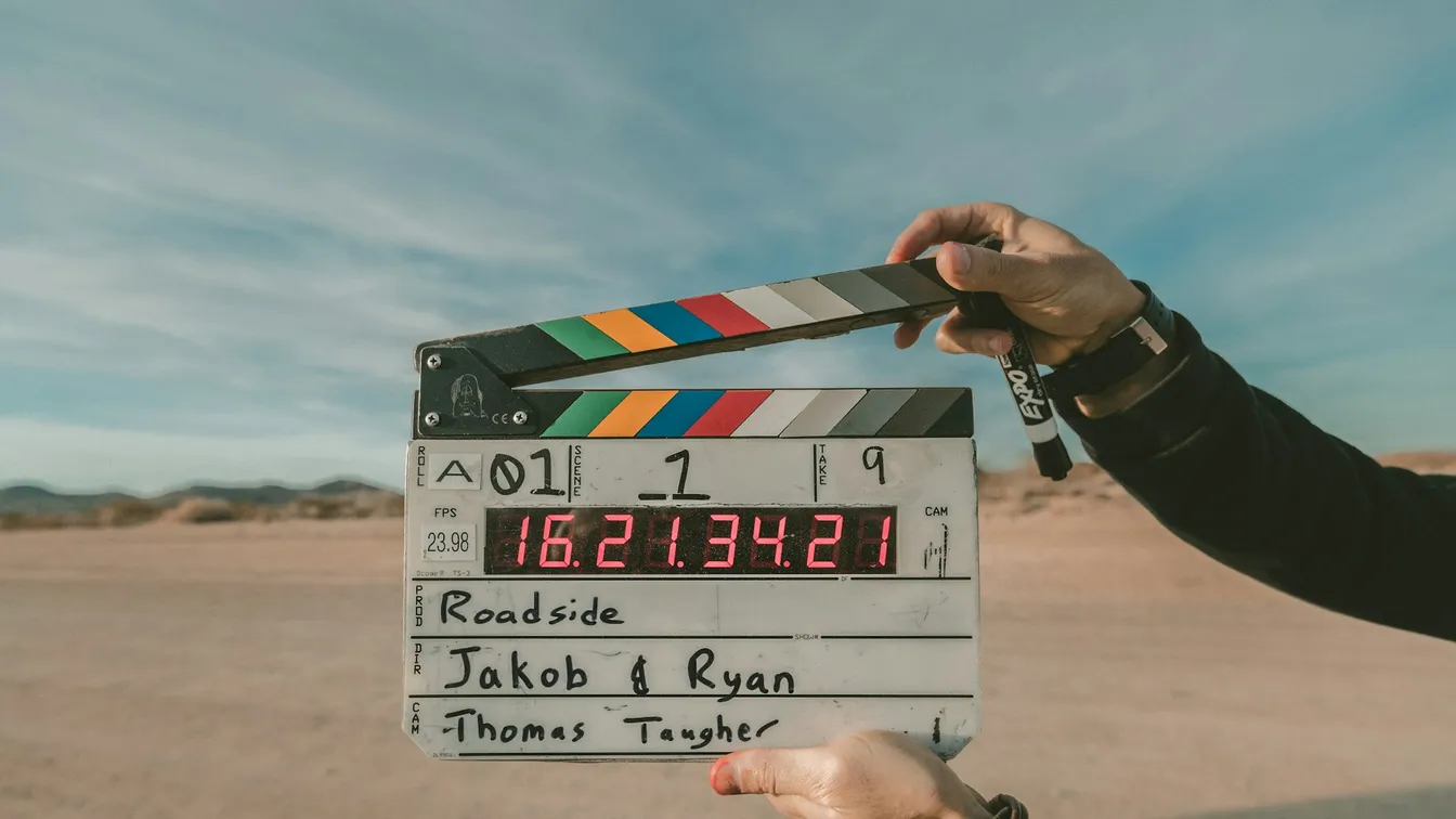 a person holding up a clapper board in the desert