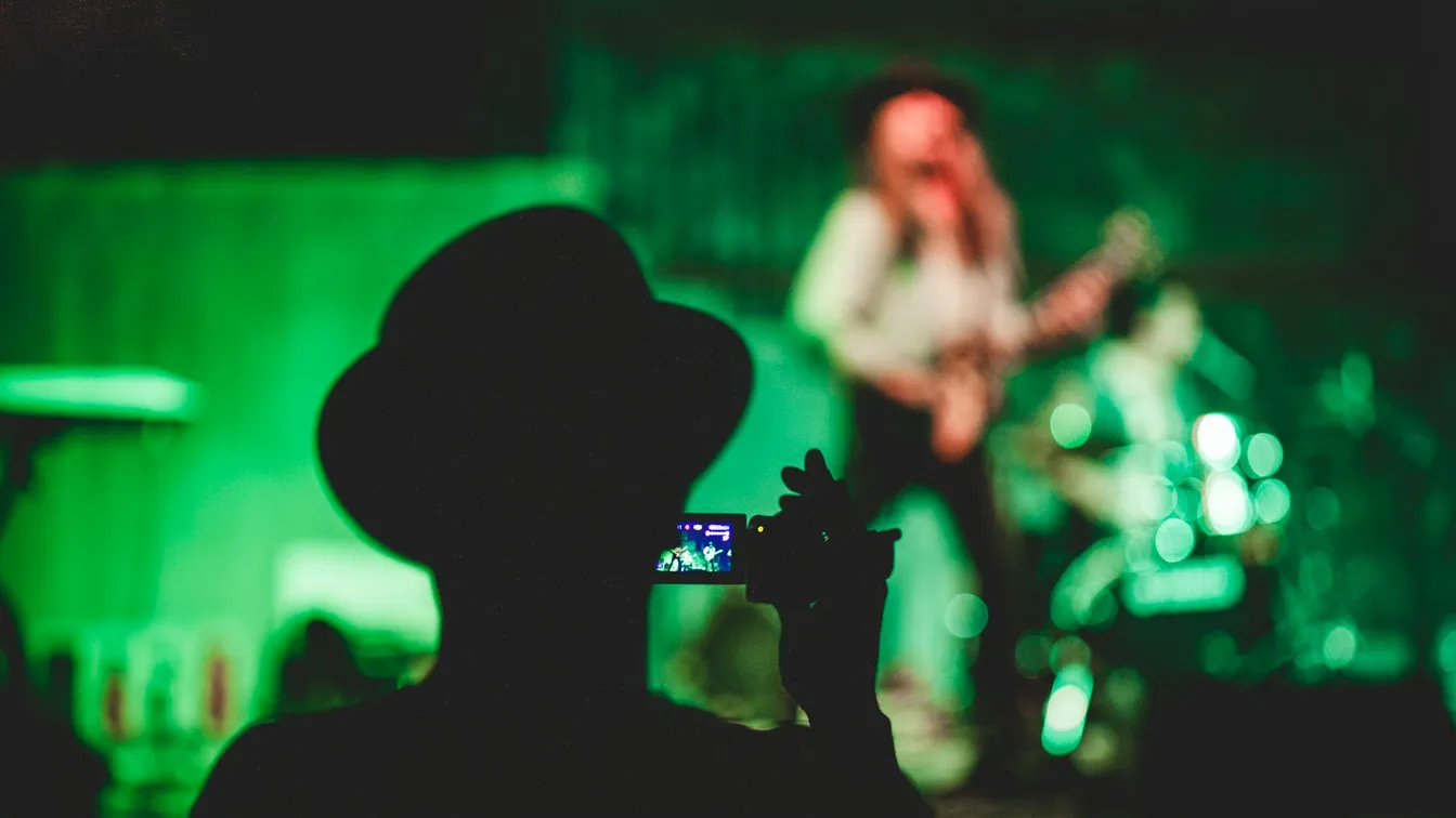 a person taking a picture of a band at a concert