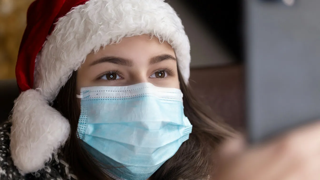 a girl in a santa hat wearing a face mask